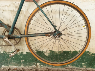 The yellow rear wheel of an old bicycle.
