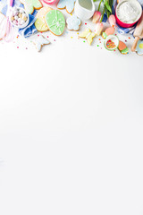 Sweet Easter baking cooking background with traditional Easter bunny and egg cookies, sugar sprinkles, ingredients, utensils. White table background copy space layout