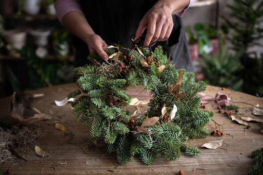 Woman making Christmas wreath of spruce, step by step. Concept of florist's work before the Christmas holidays..