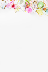 Sweet Easter baking cooking background with traditional Easter bunny and egg cookies, sugar sprinkles, ingredients, utensils. White table background copy space layout