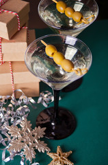 Two glasses of martini with olives, gift boxes and toy snowflake.