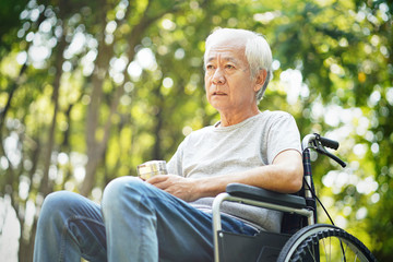 sad asian senior man sitting in wheelchair