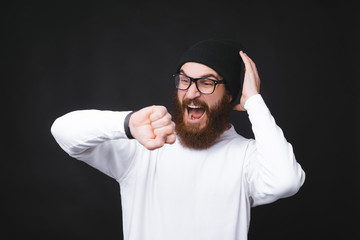 Amazed man looking shocked at smartwatch standing over dark background