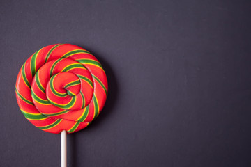 Rainbow color lollipop hard caramel on the stick on black background. Copy space. Top view.