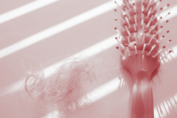 Tangled hair near comb on the table, red tone.