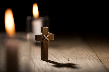 Wooden cross and candles on dark background