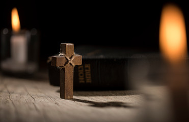 Holy Bible and wooden cross on dark background