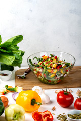 Bowl full of salad from different eco vegetables with ingredients and spices on the table. Healthy diet food concept.