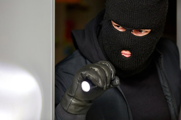 Burglar breaking in at night with flashlight