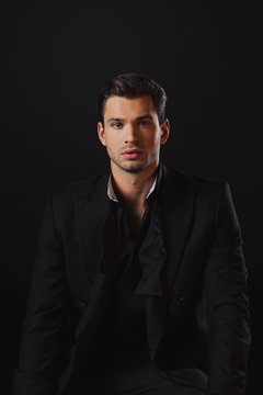 handsome man in suit looking at camera isolated on black