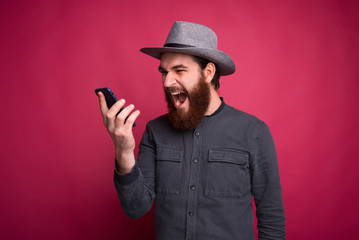 Photo of angry bearded man tallking on smartphone