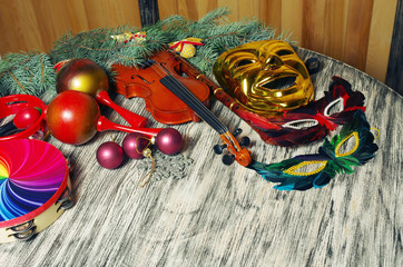 Carnival still life. Carnival masks, violin, flute, maracas, tambourine on a decorated table.