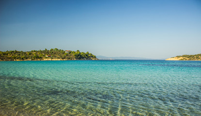 Greece beach cozy Aegean sea lagoon transparent aquamarine shallow water with horizon background view islands coast line in summer tine clear weather