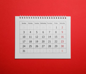 Paper calendar on red background, top view