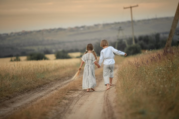 Two children running down a country road in shirt and dress.