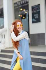 A beautiful young cheerful girl climbs the steps to or from the building.