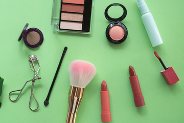 A collection of make up and cosmetic products arranged on a pastel green background.beauty concept.