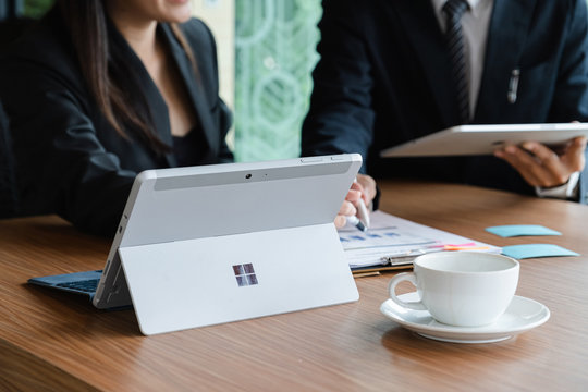 CHIANGMAI, THAILAND - AUG 31, 2019 : Microsoft Surface tablet on desk with businesman and businesswoman discussing background. created by Microsoft for Windows 10.