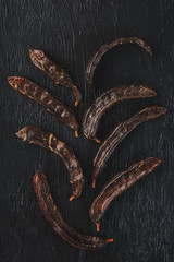 The fruit of the carob tree on black textured background in the form