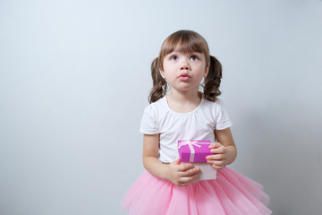 .little girl child with a surprised facial expression looks in a gift box. Happy New Year, Merry Christmas, Happy Birthday