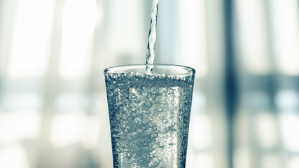 Nalewanie oczyszczonej świeżej wody do picia z butelki na stole w salonie - obrazy, fototapety, plakaty