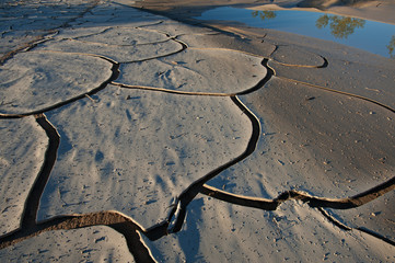 Dried mud and rain pool with reflections of mountains, Mesquite Flat Sand Dunes, Death Valley...