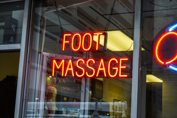 Fototapeta na wymiar Red florescent sign in a large store window that says Foot Massage