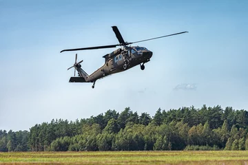 Muurstickers Militaire helikopter die in de lucht vliegt met bos op de achtergrond © bzzup