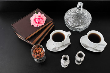 Tea items, books and a rose over a black surface