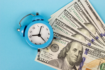 money and alarm clock on a blue background, copy spaсe