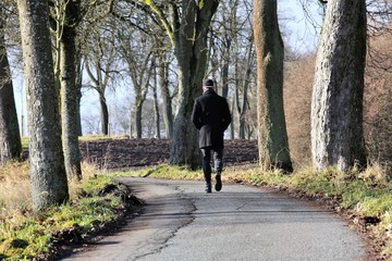 A young man walks down a lonely lane on a bright day in Bavaria, Germany