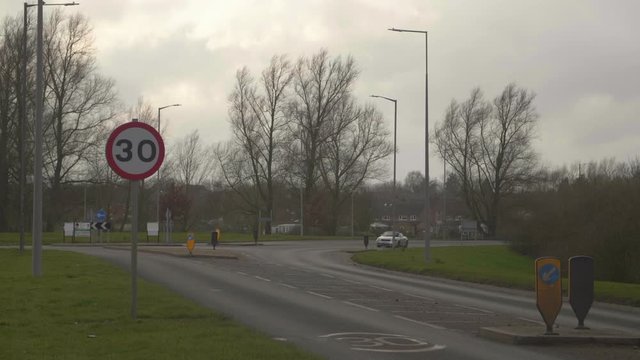 Cars carefully driving through a roundabout at dusk in England.