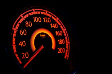 Close up of red illuminated car speedometer.
