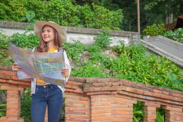 Naklejka na ściany i meble Smiling woman traveler in doi suthep temple chiangmai landmark in thailand holding world map with backpack on holiday, relaxation concept, travel concept