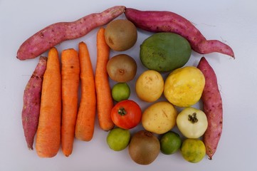 Vegetables, fruits and starches on white background. Potatoes, kiwi fruit, carrots, mango, tomatoes, limes and passion fruit. Healthy food concept.
