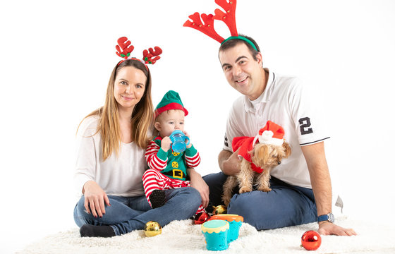 Study photo of a couple with a baby and a dog sitting on the floor disguised as Christmas with a white background