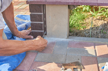 A worker installs panels brown siding on the facade of the house