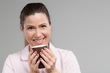 smiling middle-aged with a cup of fresh coffee or tea in her hand 