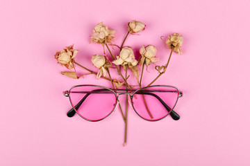 pink glasses in colors. flat lay. Glamor and style. Glasses for women. Pink glasses on a pink background decorated with dried roses.