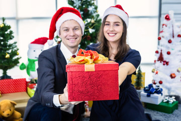 Obraz na płótnie Canvas Happy new year 2020 concept,Happy couple holding exchanging gifts and Give a present in Christmas and New Year's Eve party Christmas tree background After finishing business work