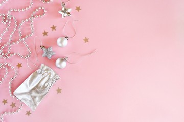 Christmas composition of silver decorations on a pastel pink background. Minimalistic holiday concept. Top view, flat lay with copy space for text .