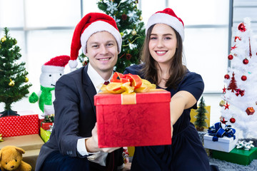 Obraz na płótnie Canvas Happy new year 2020 concept,Happy couple holding exchanging gifts and Give a present in Christmas and New Year's Eve party Christmas tree background After finishing business work