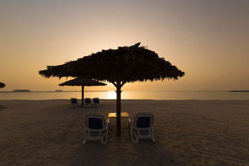 UAE, landscape sea, sunset, beach umbrella and sunbeds