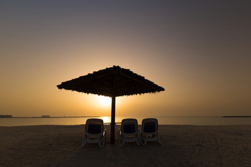 UAE, landscape sea, sunset, beach umbrella and sunbeds