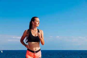 woman on the run sports runs on the beach listening to music