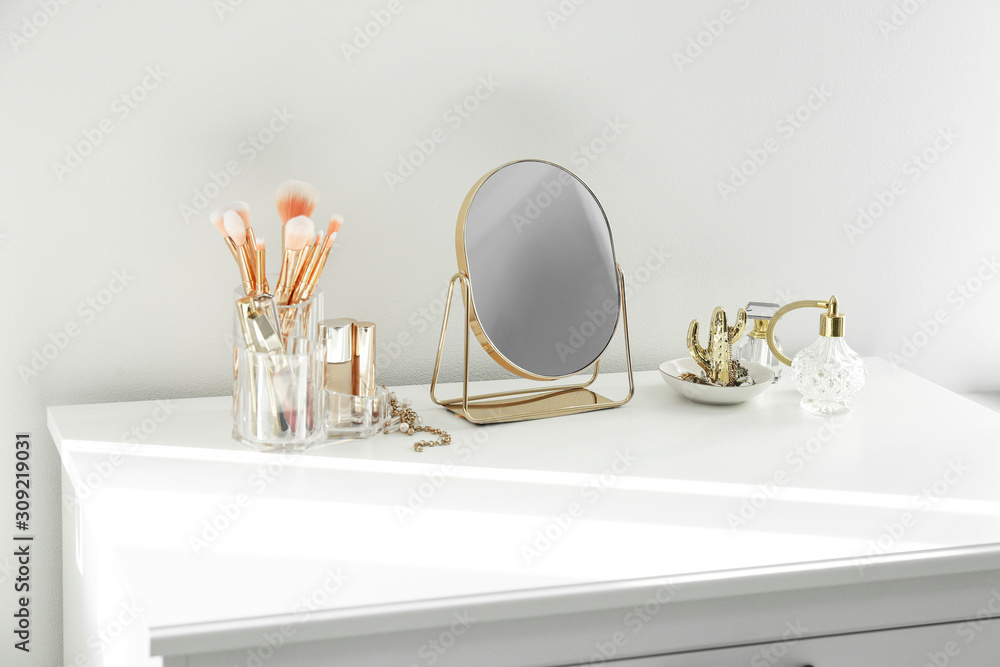 Wall mural small mirror and makeup products on white dressing table indoors