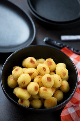 Close-up of a black bowl of pan fried stuffed potato gnocchi, selective focus, studio shot