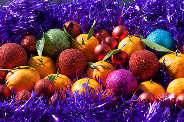 Christmas balls and oranges on purple tinsel