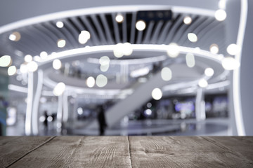 Empty wooden surface and blurred view of shopping mall. Space for design