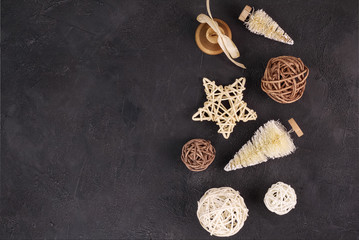 Christmas holiday background: wicker stars and balls on a black background. Place for text. Top view. Flat lay
